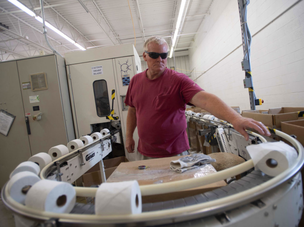 Keystone employee watching toilet paper roles as they come across the line. 