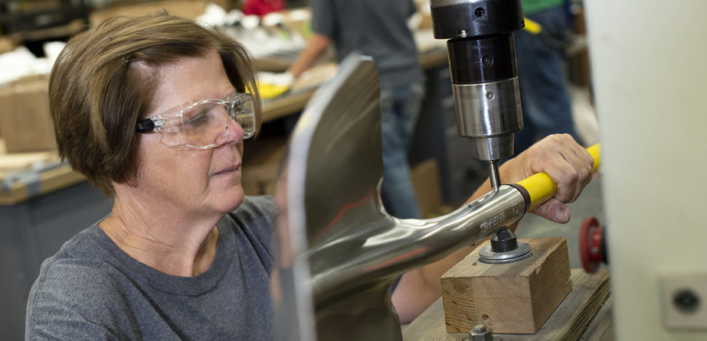 Keystone Employee using the rivet machine to attached a shovel head to the handle. 