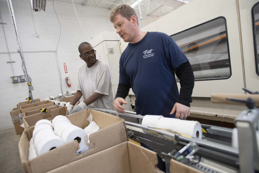 Keystone employees pack toilet paper roles into boxes.