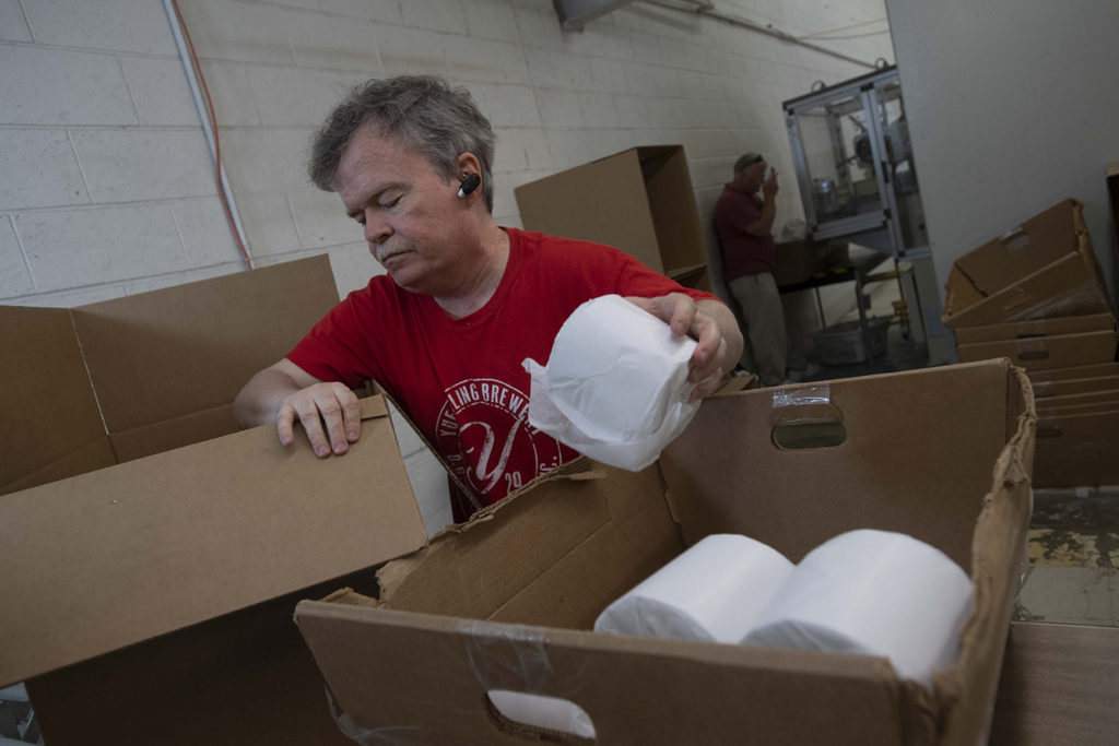 Keystone employee packs toilet paper roles into boxes.